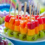 tavola con buffet piena di frutta e colorati spiedini di frutta estiva con kiwi, melone e anguria