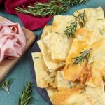 vassoio con pizza bianca scrocchiarella e rosmarino, vassoio con mortadella accanto