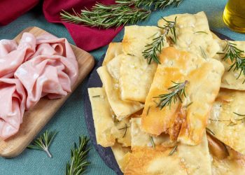 vassoio con pizza bianca scrocchiarella e rosmarino, vassoio con mortadella accanto