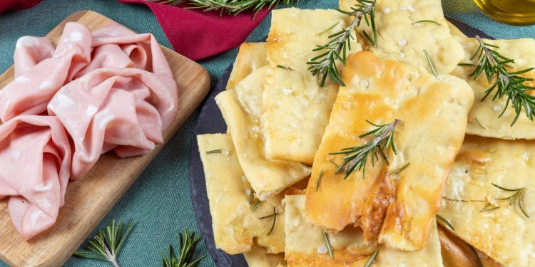 vassoio con pizza bianca scrocchiarella e rosmarino, vassoio con mortadella accanto