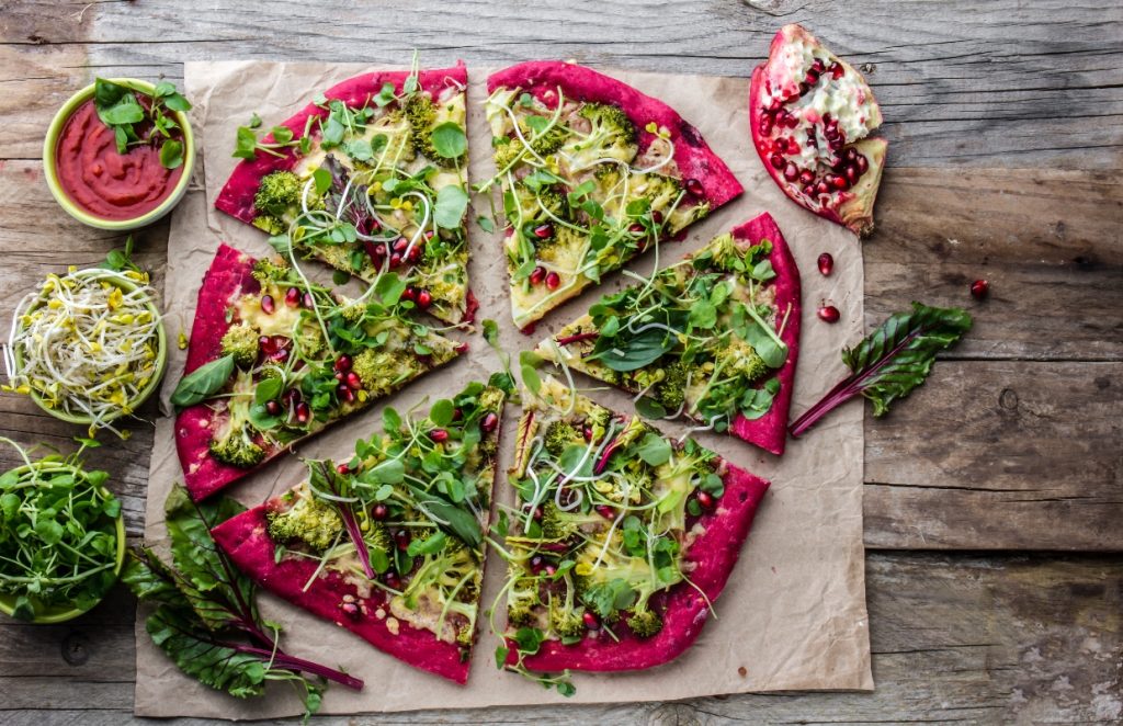 su tavolo di legno pietra refrattaria con pizza di verdure e melagrana