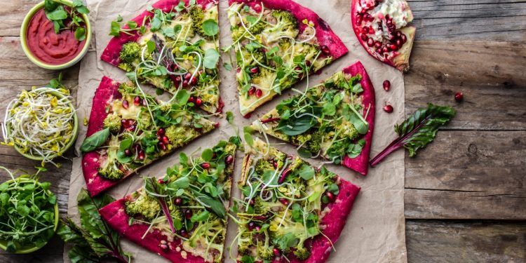 su tavolo di legno pietra refrattaria con pizza di verdure e melagrana