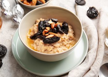 piattino e ciotola con cereali e prugne secche