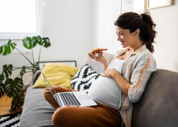 una donna in gravidanza che mangia una pizza con la mortadella