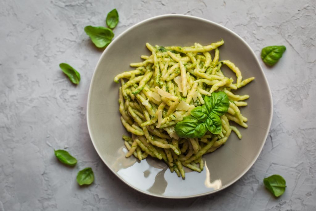 su piano di lavoro di marmo, piatto grigio con le trofie al pesto e foglie di basilico