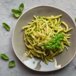 su piano di lavoro di marmo, piatto grigio con le trofie al pesto e foglie di basilico