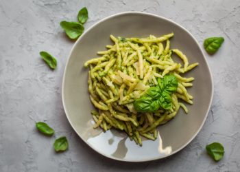 su piano di lavoro di marmo, piatto grigio con le trofie al pesto e foglie di basilico