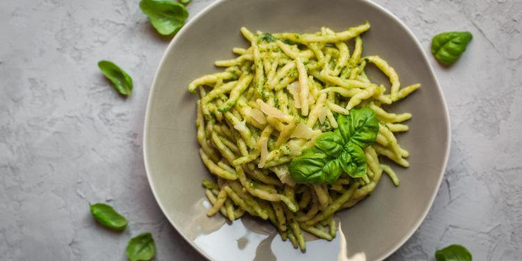 su piano di lavoro di marmo, piatto grigio con le trofie al pesto e foglie di basilico