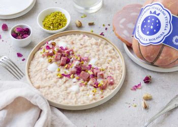 Risotto con mortadella posizionato su un tavolo con tovaglia bianca