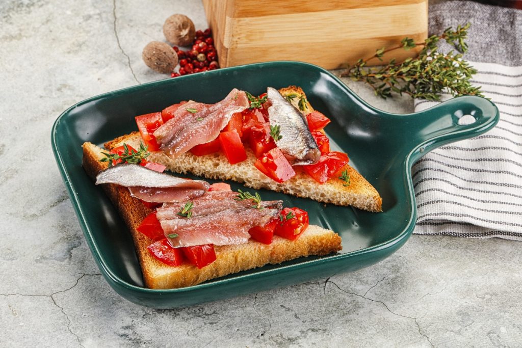 su tavolo da cucina di marmo, in una padella rettangolare un toast tagliato a triangolo con pomodorini