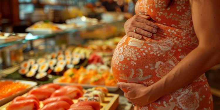 Una donna in gravidanza davanti a una tavolata con salmone crudo e affumicato